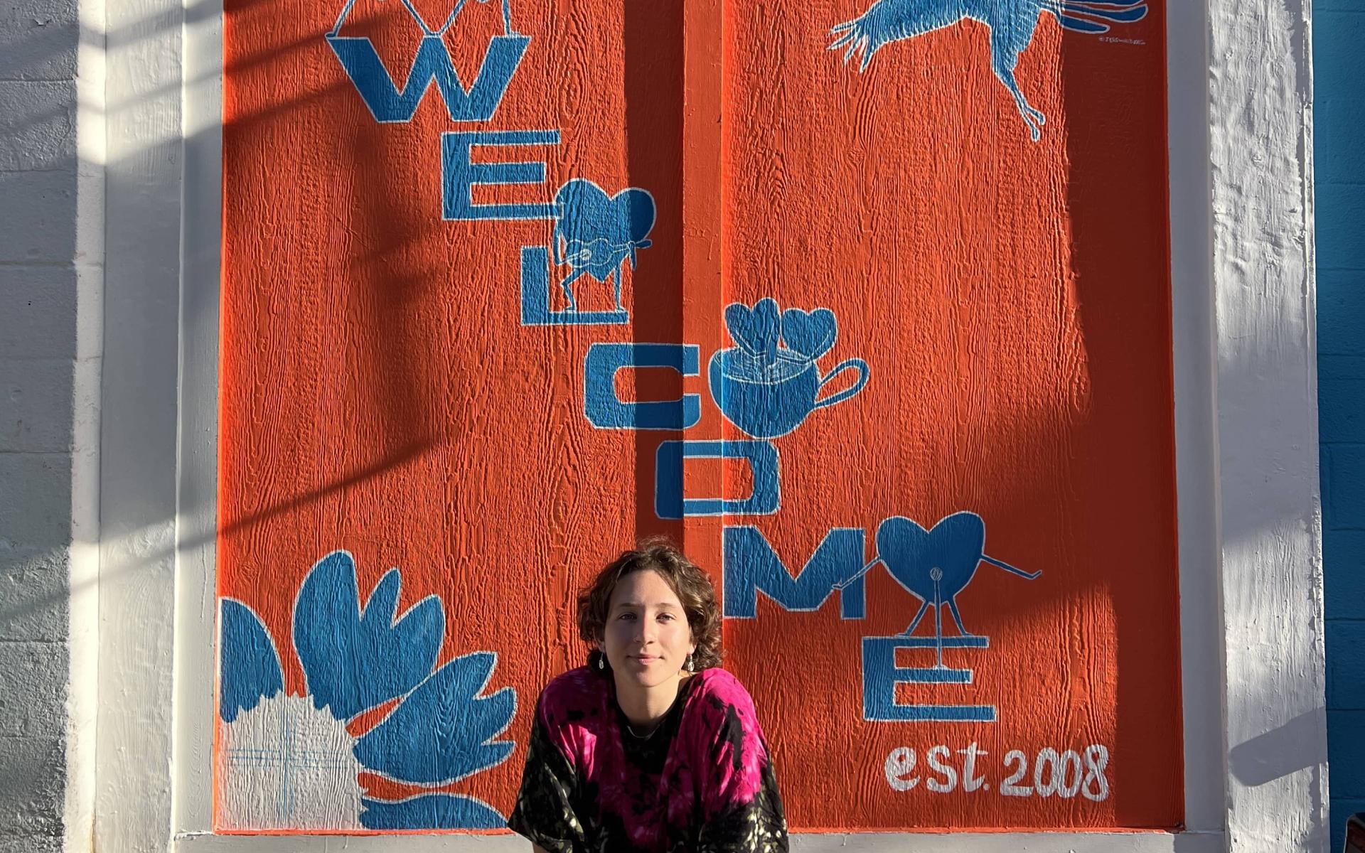 Artist sitting in front of her mural